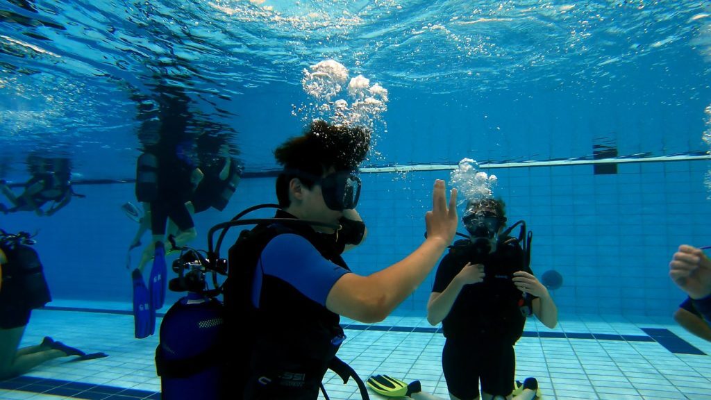 Échange de signes entre deux plongeurs étudiants d'Into The Blue sous l'eau